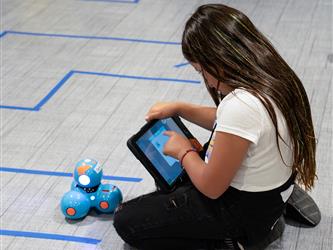A child programming a Dash robot using an iPad