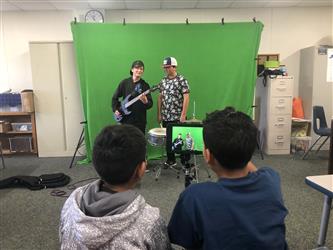 Students filming video using green screen background